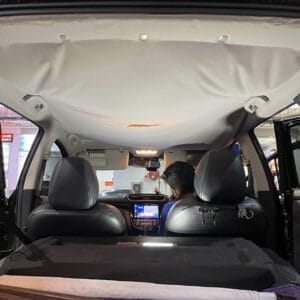 Roof Lining Restoration Processing Step 1: Severely sagging roof lining fabric inside the vehicle, almost detached, with the worker preparing to remove it for restoration.