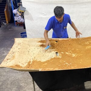 Roof Lining Restoration Processing Step 4: Worker using a brush to remove aged foam residue from the roof board surface after the old roof lining fabric has been removed.
