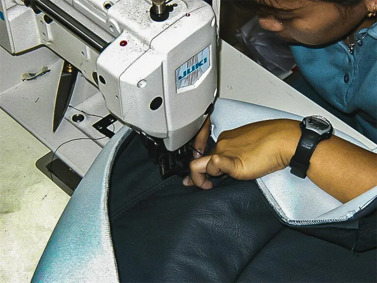 Car Interior Restoration Singapore - Seamstress sewing leather upholstery with precision, working on a custom-fit seat cover.
