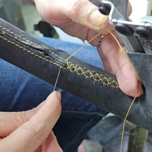 Car Interior Restoration Singapore - hand-stitching a steering wheel with precision, carefully sewing each stitch to ensure a perfect finish.