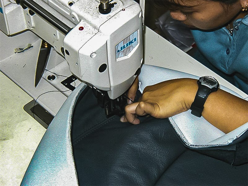 Automotive upholstery specialist sewing a leather car seat in Singapore