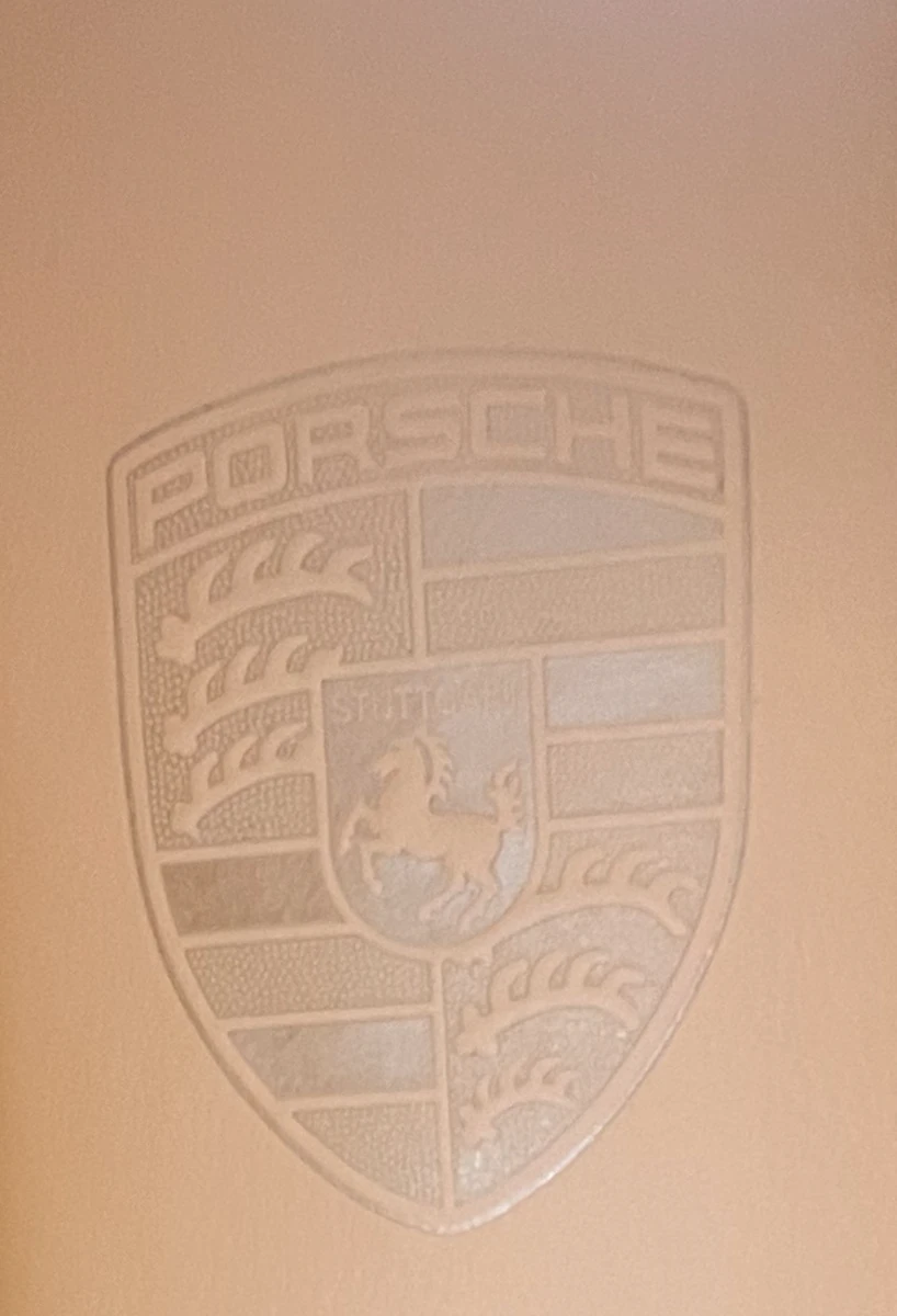 Close-up of a custom Porsche crest embossed on a cognac leather centre armrest